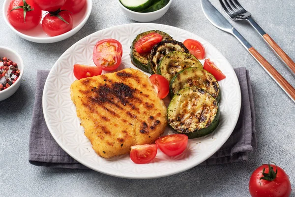 Izgarada kızarmış tavuk ve kabak şnitzel. Tabakta taze domates. Yemek için hazır..