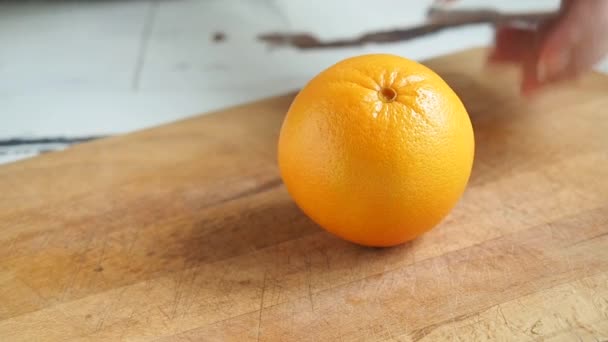 一个女人在木板屋厨房切橙子.有益健康的水果柑橘类. — 图库视频影像