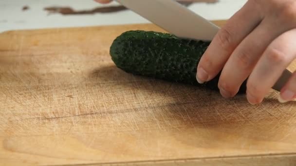 Chef mujer prepara una ensalada saludable de verduras frescas. Comida vegetariana. Cortar el pepino en una tabla de madera en una cocina casera . — Vídeo de stock