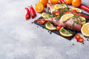 Limon dilimleri, dereotlu yeşillikler ve beton zeminde kırmızı acı biberli çiğ balık tüneği. Uzayı kopyala Sağlıklı gıda ve diyet konsepti. Balık pişirmek için gerekli malzemeler