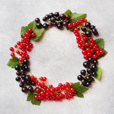 Kopya alanı ile gri bir masada siyah ve kırmızı kuş üzümü taze çilek