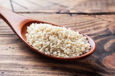 Tahta kaşıkta doğal susam tohumları. Tahta masa. Boşluğu kopyala