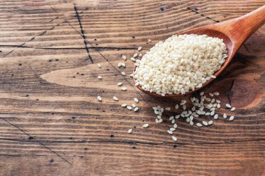 Tahta kaşıkta doğal susam tohumları. Tahta masa. Boşluğu kopyala