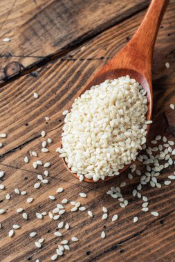 Tahta kaşıkta doğal susam tohumları. Tahta masa. Boşluğu kopyala