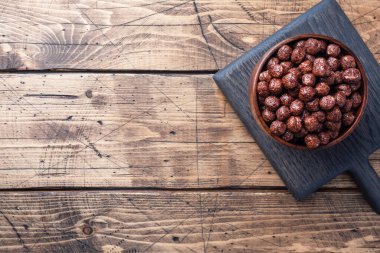 Doğal mısır gevreğindeki çikolata taneleri sütlü kahvaltı için kurutuldu. Tahta tablo Boşluğu kopyala