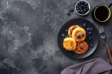 Yabanmersinli süzme peynirli börek. Peynirli peynirli kekler, koyu beton arka planda krepler. Boşluğu kopyala