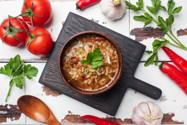 Pirinç ve sebzeli vejetaryen çorbası. Sarımsaklı acı biber domatesleri. Ahşap kırsal arka plan, doğal bambudan yapılmış plakalar.