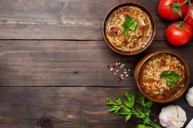 Pirinç ve sebzeli vejetaryen çorbası. Sarımsaklı acı biber domatesleri. Uzayı kopyala ahşap kırsal arkaplan, doğal bambudan yapılmış plakalar