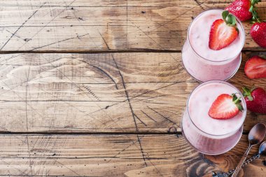 Ahşap bir arka plan üzerinde gözlük taze çilek ile ev yapımı yoğurt. Seçici odak. Kopyalama alanı