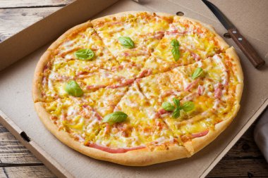 Ahşap bir masa üzerinde bir karton kutu içinde taze pişmiş pizza