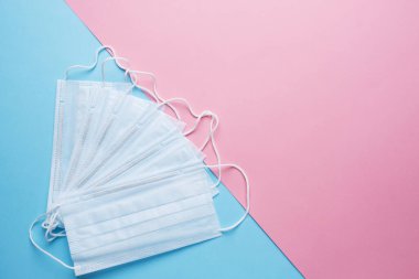 Tek kullanımlık tıbbi yüz maskeleri. Virüsün önlenmesi kavramı. Pembe mavi arka plan. Boşluğu kopyala
