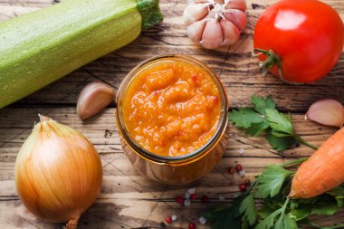 Kabak domatesinden ev yapımı havyar ve ahşap arka planda cam bir kavanozda soğan. Ev yapımı konserve, konserve sebze konservesi.