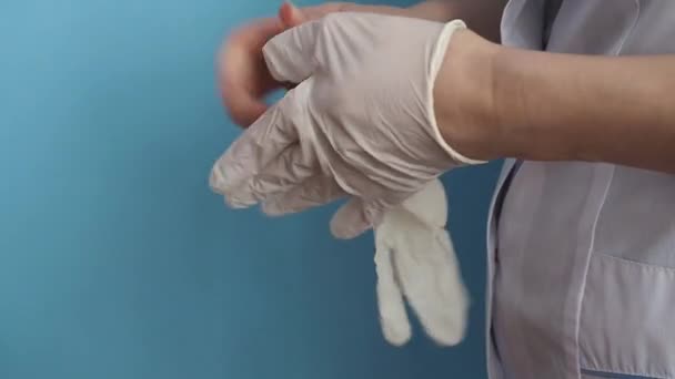 一位穿着白衣的医生把医用胶乳手套戴在手上 — 图库视频影像