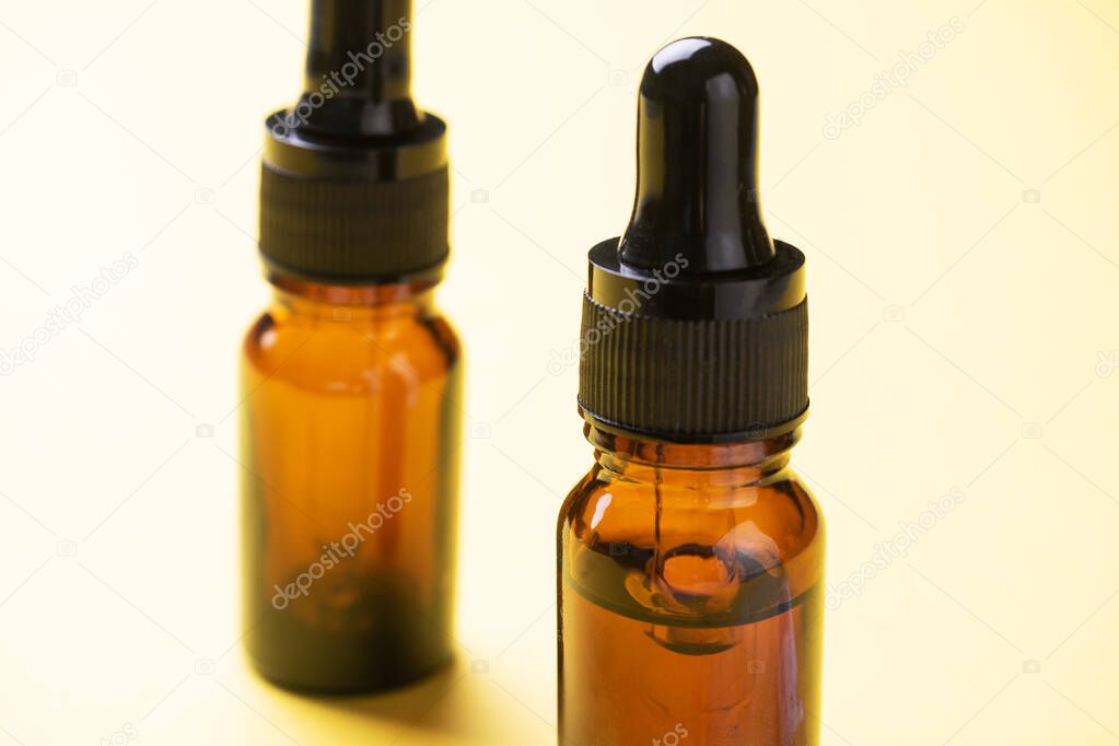 Bottle of cosmetic oil with a pipette on a yellow background. Copy space. Selective focus