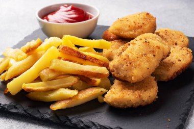 Kızarmış patates ve ketçap soslu tavuk nugget. Sağlıksız gıda konsepti. Gri beton masa. Boşluk kopyala..