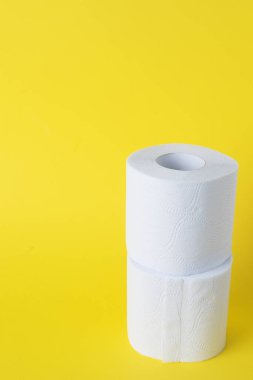 Sarı arka planda beyaz tuvalet kağıdı ruloları. Boşluğu kopyala
