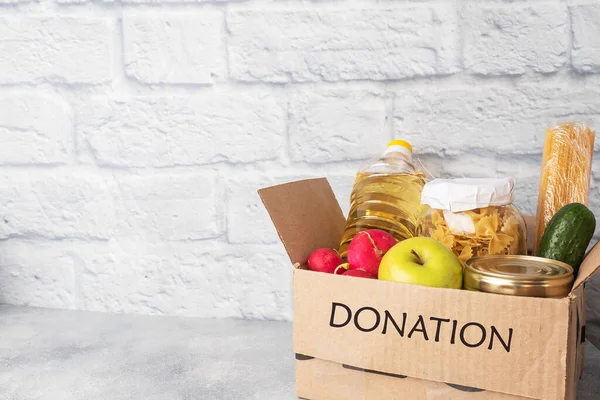 Donation of food collected in a box. Gray background. Copy space