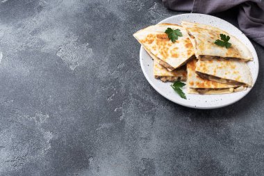 Peynirli ve mantarlı Quesadilla parçaları maydanoz yapraklı bir tabakta. Somut arkaplan kopyalama alanı