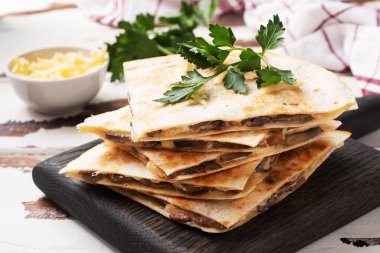 Tahta tezgahta maydanoz yapraklı peynirli, mantarlı Quesadilla parçaları. Ahşap arkaplan kopyalama alanı