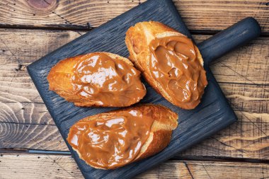 Ekmek baget ekmekli sandviçler ve haşlanmış süt ezmesi. Ahşap arkaplan