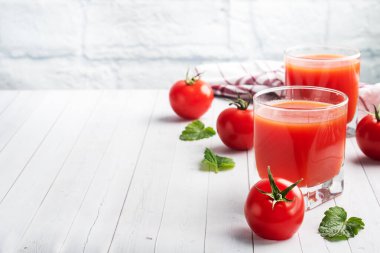 Cam bardakta domates suyu ve dalda taze olgun domates. Kopyalama alanı olan beyaz tahta arkaplan