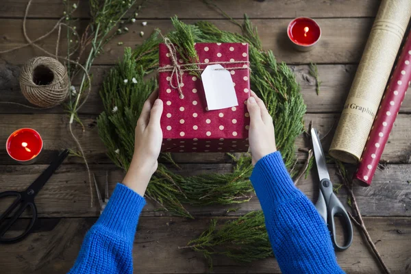 나무 테이블 배경에 놓인 크리스마스 선물을 들고. — 스톡 사진
