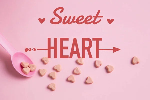 Una cuchara rosa con caramelos de corazón rosa —  Fotos de Stock