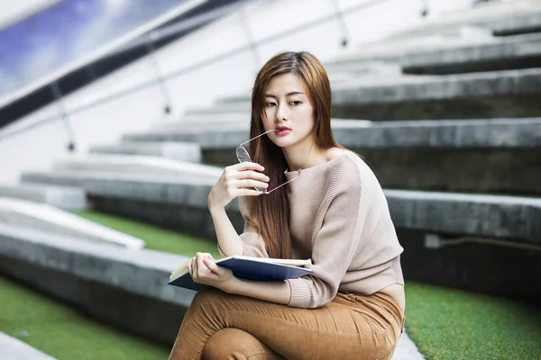 Asian woman thinking with a book