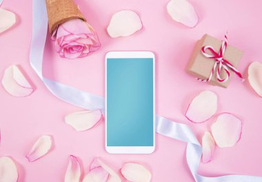 Hareket eden telefon aygıt üzerinde pastel pembe backgrou gül dekorasyonu ile