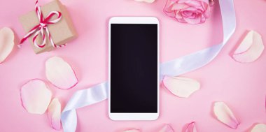 Hareket eden telefon aygıt üzerinde pastel pembe backgrou gül dekorasyonu ile