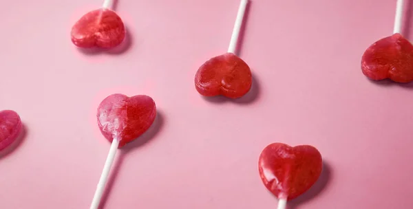 Dulces de piruleta en forma de corazón del día de San Valentín sobre papel rosa pastel —  Fotos de Stock