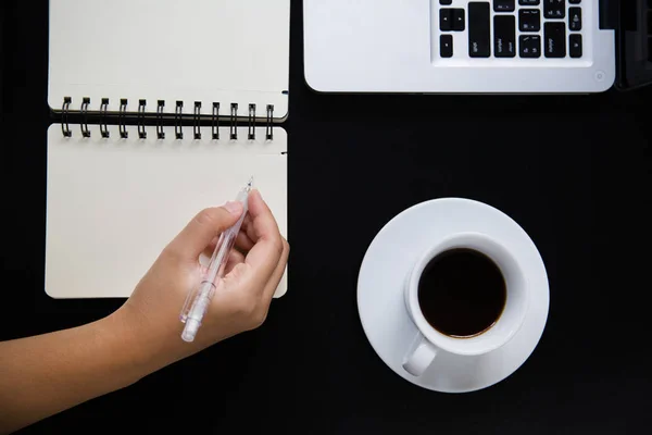 Кофейная чашка и ноутбук с запиской на черном столе — стоковое фото