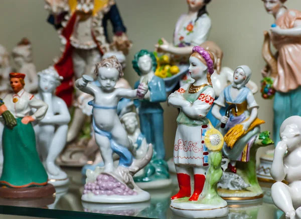 Коллекция Различных Красочных Старинных Фарфоровых Статуэток Выставлена Стеклянной Полке — стоковое фото