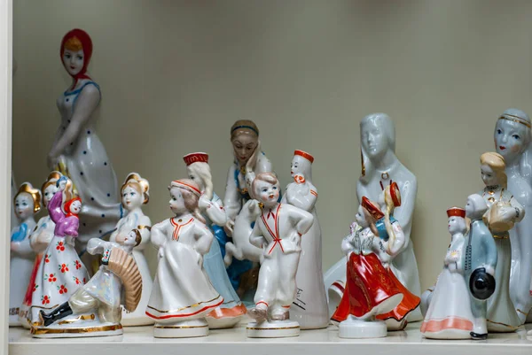 Assortment of rare porcelain figurines on glass shelf — Stock Photo, Image