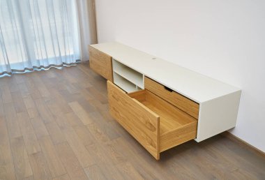 Çağdaş yüzen medya dolabı oturma odasında. Ahşap duvar açık çekmeceleri olan bir dolap.