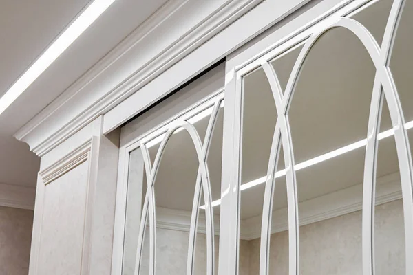 Sliding mirror wardrobe doors with overlays decor. White sliding mirror wardrobe. Close-up