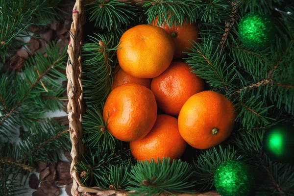 Weihnachtskugeln, Mandarinen und Tannenbaum im rustikalen Weidenkorb — Stockfoto