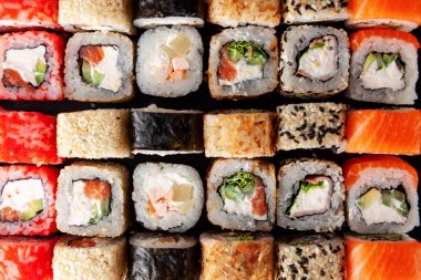 Siyah arka plan üzerine çeşitli suşi rulo