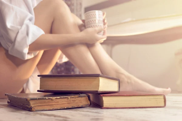Женщина читает книгу и пьет кофе в своем комфортном доме — стоковое фото