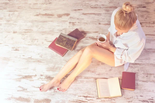 Frau liest ein Buch und trinkt Tee in ihrem gemütlichen Zuhause — Stockfoto