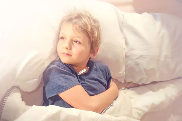 子供の病気発熱と温度計が付いているベッドで — ストック写真