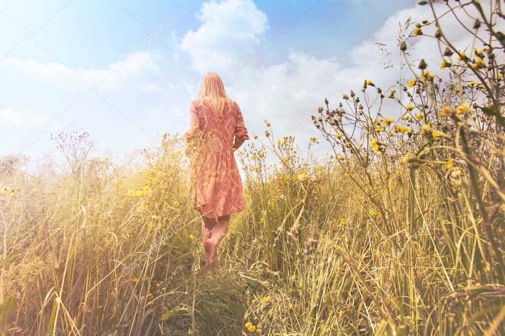 dreamy woman walking in nature towards the sun and the unknown infinite