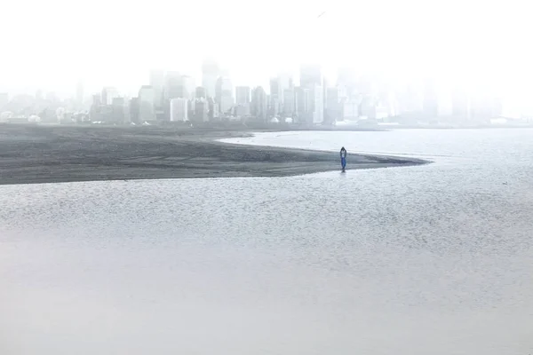 Pessoa solitária se afasta da grande cidade imersa no nevoeiro — Fotografia de Stock