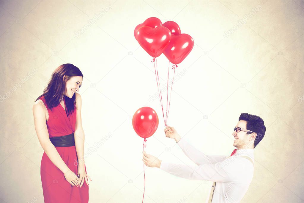 Man approaching woman giving her red heart shape balloons in a valentine's day