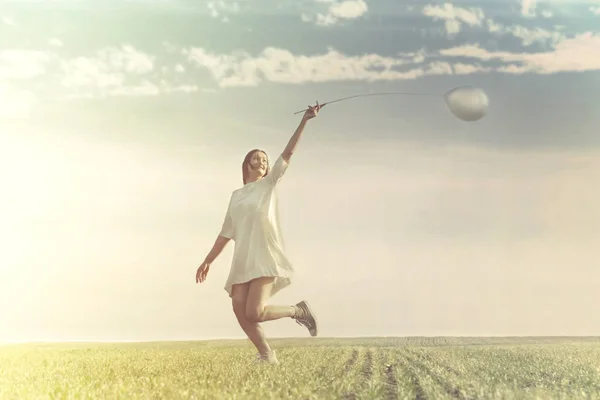 Jeune femme s'amusant avec ballon dans une prairie verte — Photo