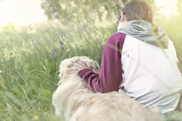 Menino e seu cachorro sentados juntos no meio da natureza — Fotografia de Stock