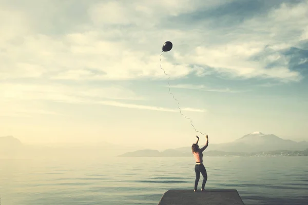 Самотня жінка намагається контролювати свою повітряну кулю, яка хоче втекти до свободи — стокове фото