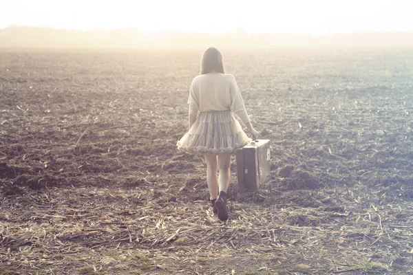 Femme avec valise marchant vers l'infini dans un lieu désert — Photo