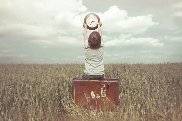 Kleiner Junge reckt eine Uhr in den Himmel in einer surrealen Landschaft — Stockfoto