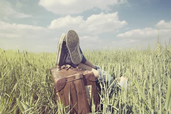 Niño descansando en un prado con los pies por encima de la maleta —  Fotos de Stock